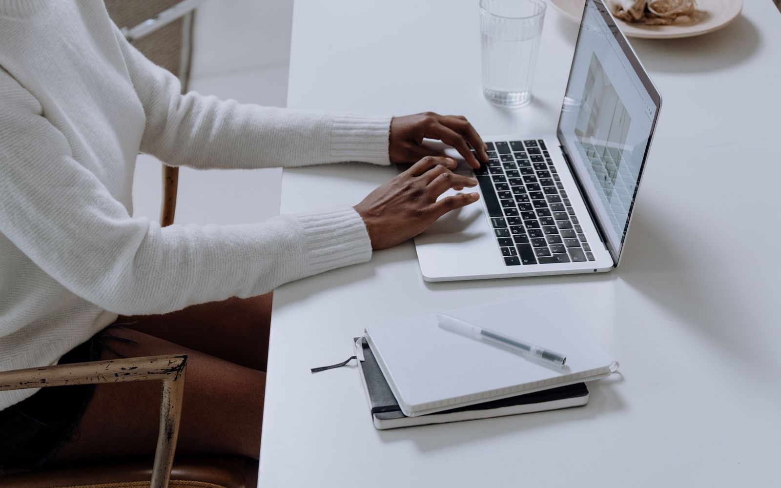 Une femme au travail sur un ordinateur portable, à une table claire.