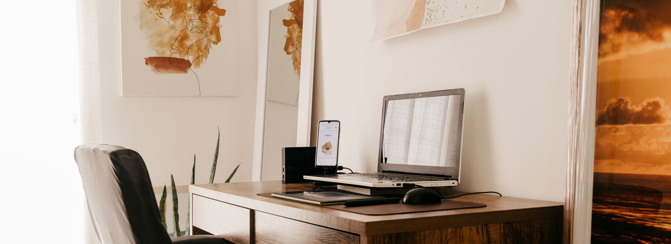 Un poste de travail dans une pièce claire, ordinateur portable posé sur un bureau de bois.