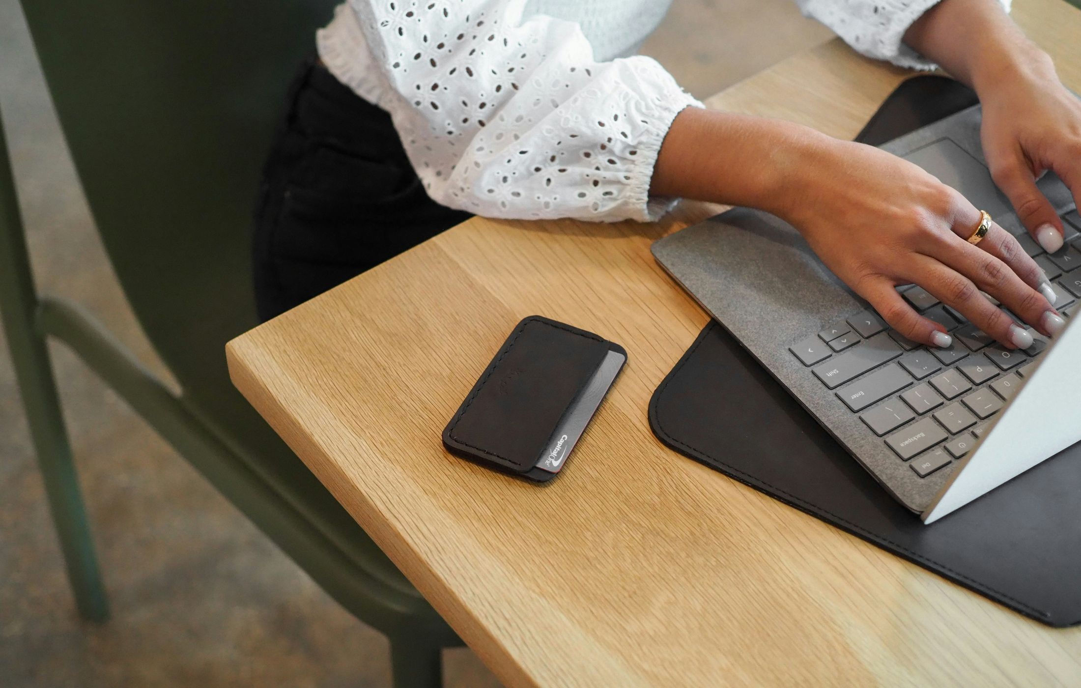 Deux mains sur le clavier d’un ordinateur portable, sur un plan de chêne clair.